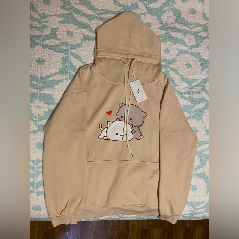 Beige hoodie with kitten graphic, soft fabric, front pocket, and tags attached